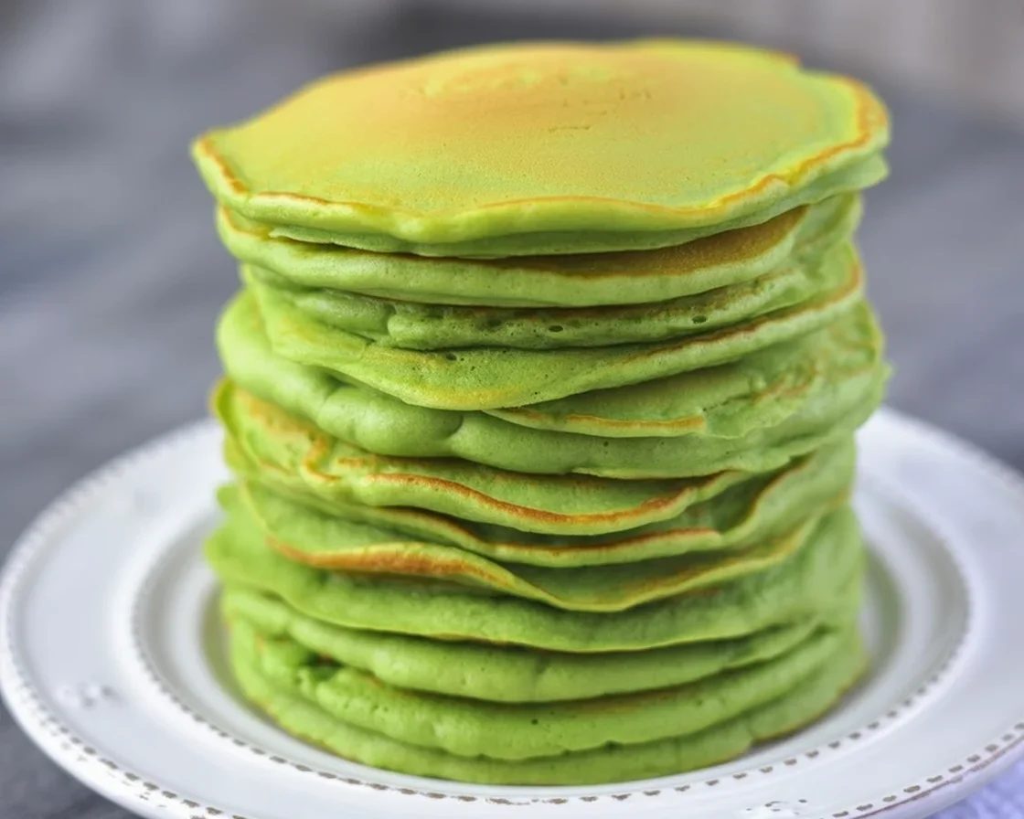 Fluffy green spinach pancakes served on a plate, nutritious for kids and families.